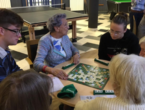 Students playing board games with elderly people at a nursing home